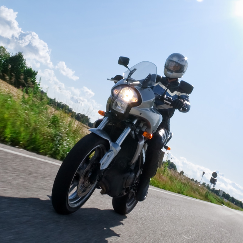 adult riding a motorcycle along a country road
